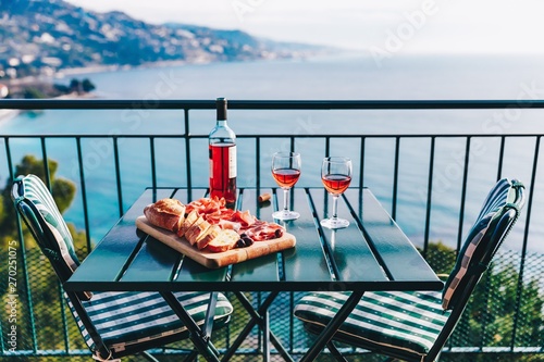 Fototapeta Naklejka Na Ścianę i Meble -  Two glasses of wine and italian snacks  with amazing view at sunset in Italy.
