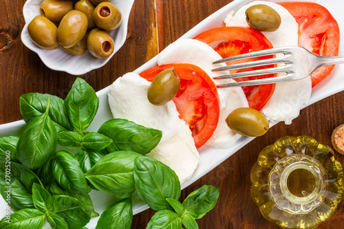 Swieza mozzarella z plastrarmi pomidora i listkami bazyli. Rustykalna kuchnia. Wegetarianskie danie. Vege salatka. photo