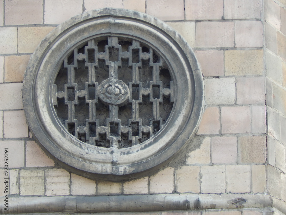 Fragment of a building wall with an architectural ornament in the form of a metal patterned circle