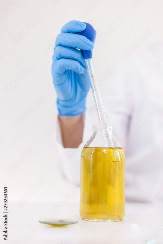 Scientist working with pharmaceutical cbd oil in a laboratory with glass dropper and a bowl Scientist working with pharmaceutical cbd oil in a laboratory with glass dropper and a bowl