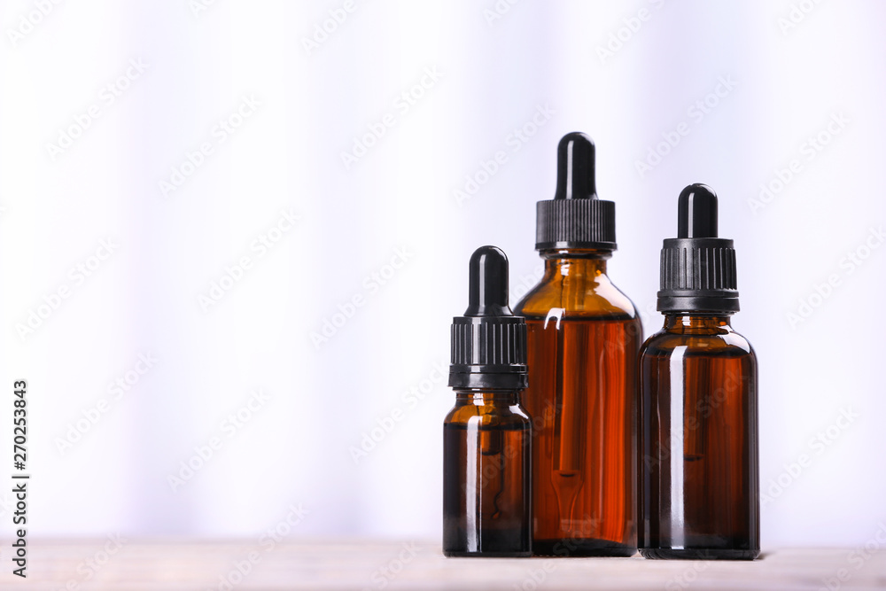 Bottles of essential oils on table against light background, space for text. Cosmetic products Bottles of essential oils on table against light background, space for text. Cosmetic products