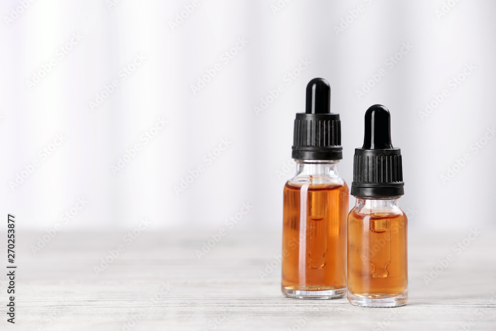 Bottles of essential oils on table against light background, space for text. Cosmetic products Bottles of essential oils on table against light background, space for text. Cosmetic products