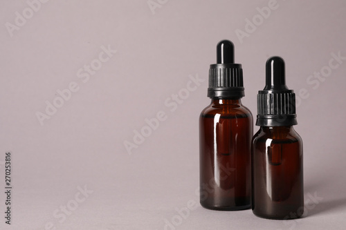 Cosmetic bottles of essential oils on color background. Space for text