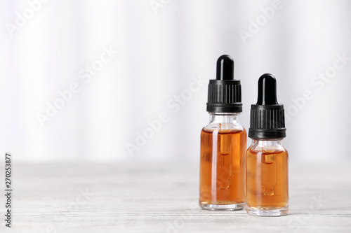 Bottles of essential oils on table against light background, space for text. Cosmetic products