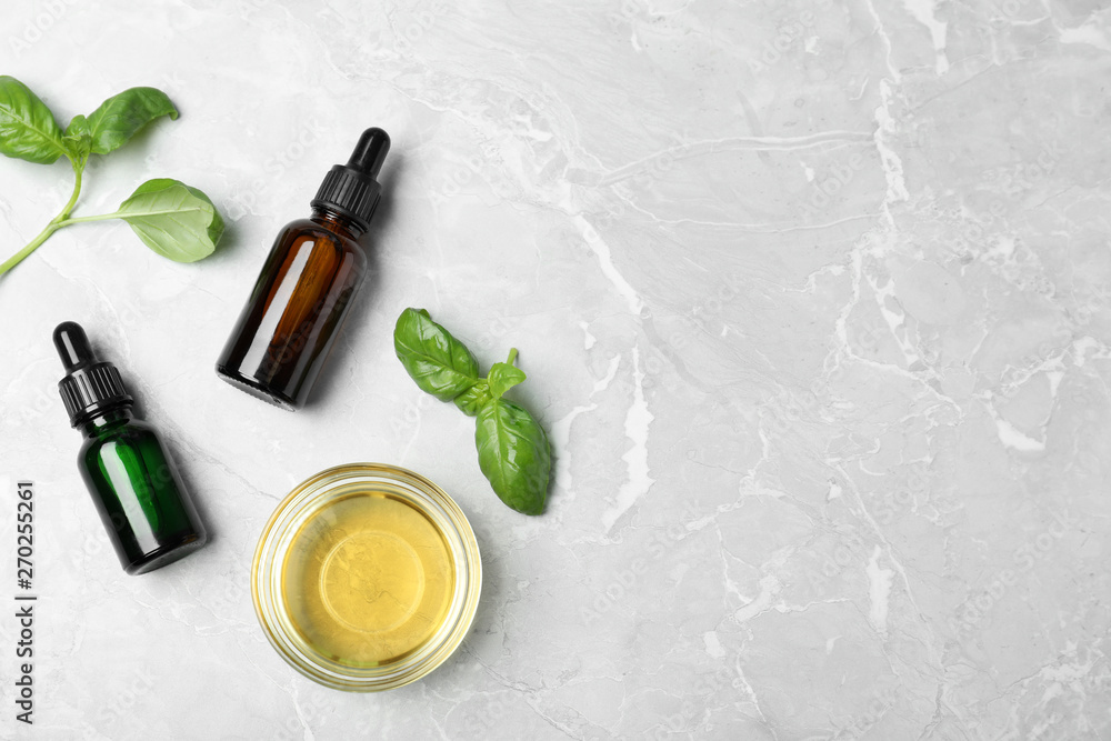 Flat lay composition with essential oils and basil on grey background. Space for text Flat lay composition with essential oils and basil on grey background. Space for text