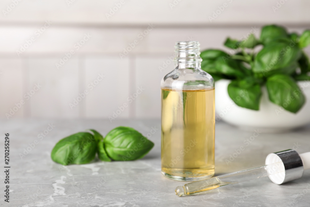 Glass bottle of essential oil, dropper and basil on table Glass bottle of essential oil, dropper and basil on table