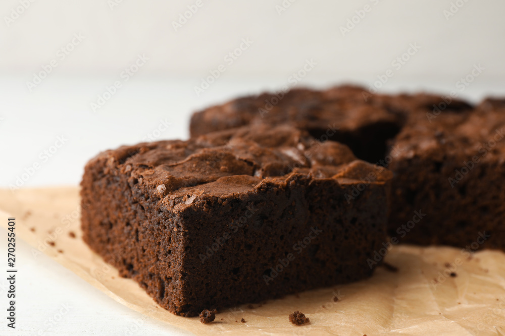 Parchment paper with fresh brownies on white table, space for text. Delicious chocolate pie Parchment paper with fresh brownies on white table, space for text. Delicious chocolate pie