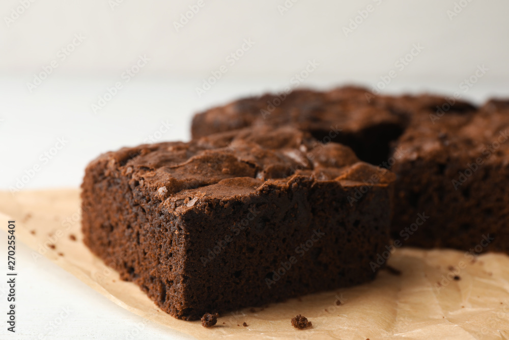 Parchment paper with fresh brownies on white table, space for text. Delicious chocolate pie