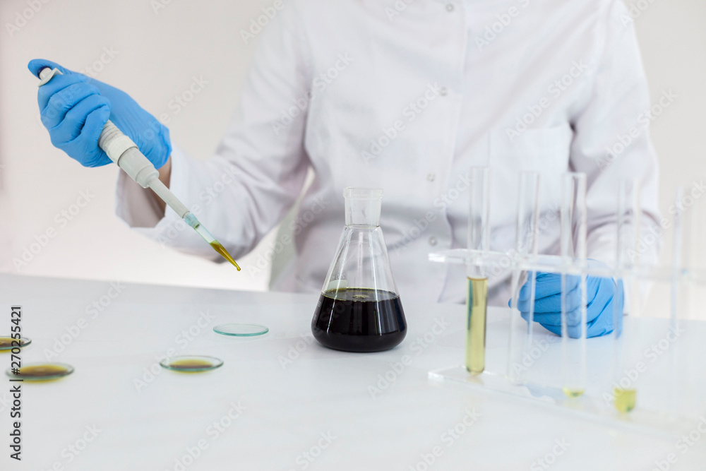Fototapeta premium Scientist with gloves checking a pharmaceutical cbd oil in a laboratory on watch glass