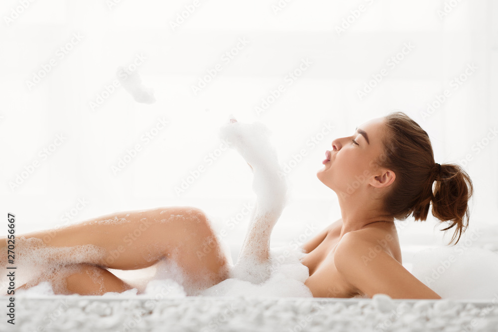 Naklejka premium Relaxing In Bathtub. Young Woman Having Fun With Foam