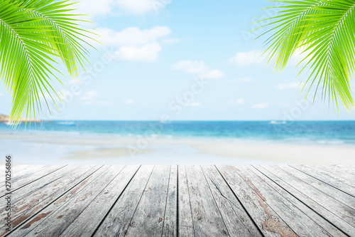 Fototapeta Naklejka Na Ścianę i Meble -  Empty wooden table or dock floor and palm leaves with blurred background, beach and beautiful sea in daytime.