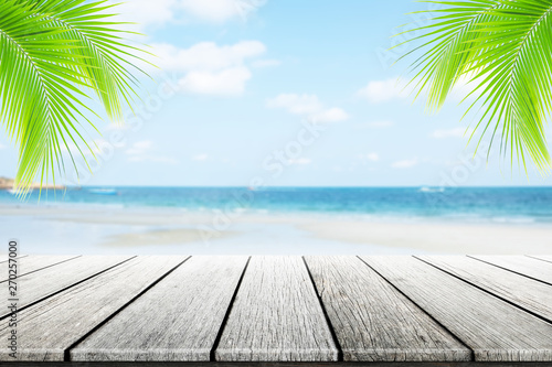 Empty wooden table or dock floor and palm leaves with blurred background  beach and beautiful sea in daytime.