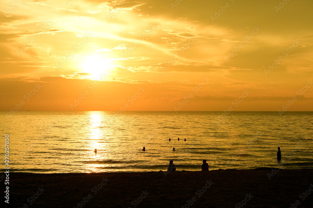 The rising sun and the golden yellow sky at the beach by the sea in the early morning