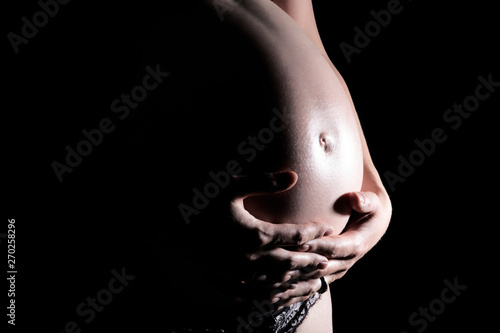 Babybauch mit Händen im Schatten Nahaufnahme