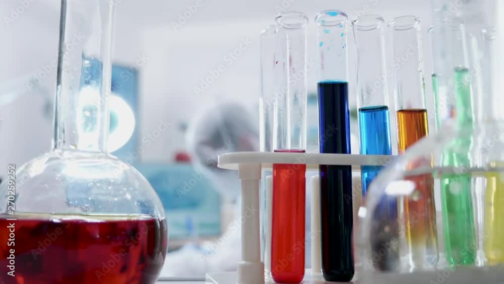 POV shot of tubes with various colored liquid approaching a researcher in the laboratory. Science and experiments