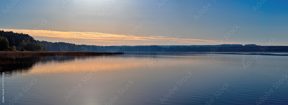 Panorama of a magnificent sunset on the lake, with a Golden-blue color