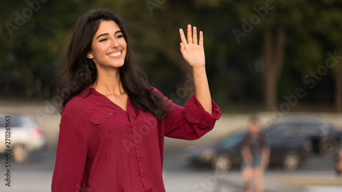 Happy woman greeting and waving hand, saying hello to friend