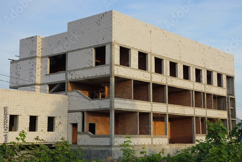 large unfinished white brick house on a building site against a blue sky