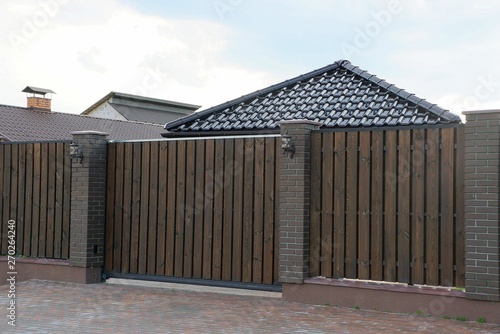brown fence and closed gates of wooden planks and bricks in the street