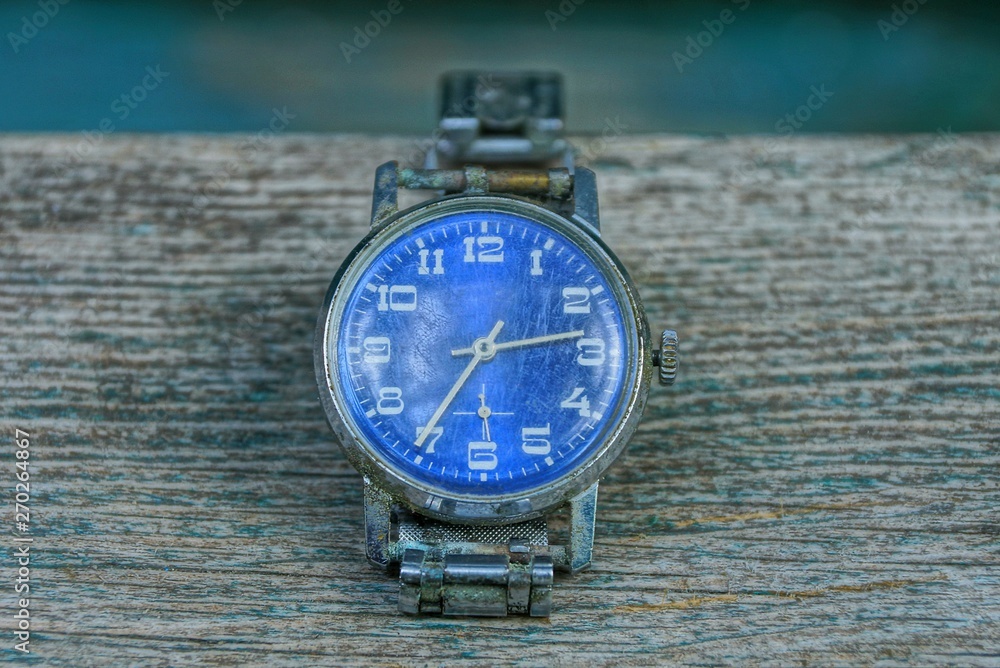 blue old shabby watch with a metal strap on a gray table blue old shabby watch with a metal strap on a gray table