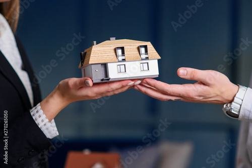 Man and woman hands holding 3d model of house.