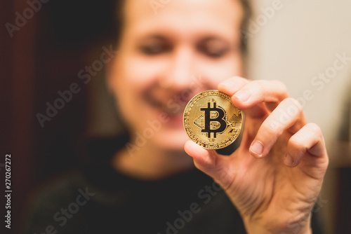 Cryptocurrency golden bitcoin coin. Man holding in hand symbol of crypto currency - electronic virtual money for web banking and international network payment, selective focus, toned
