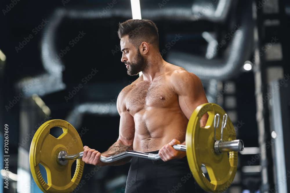 Handsome naked weightlifter lifting heavy barbell in gym Handsome naked weightlifter lifting heavy barbell in gym