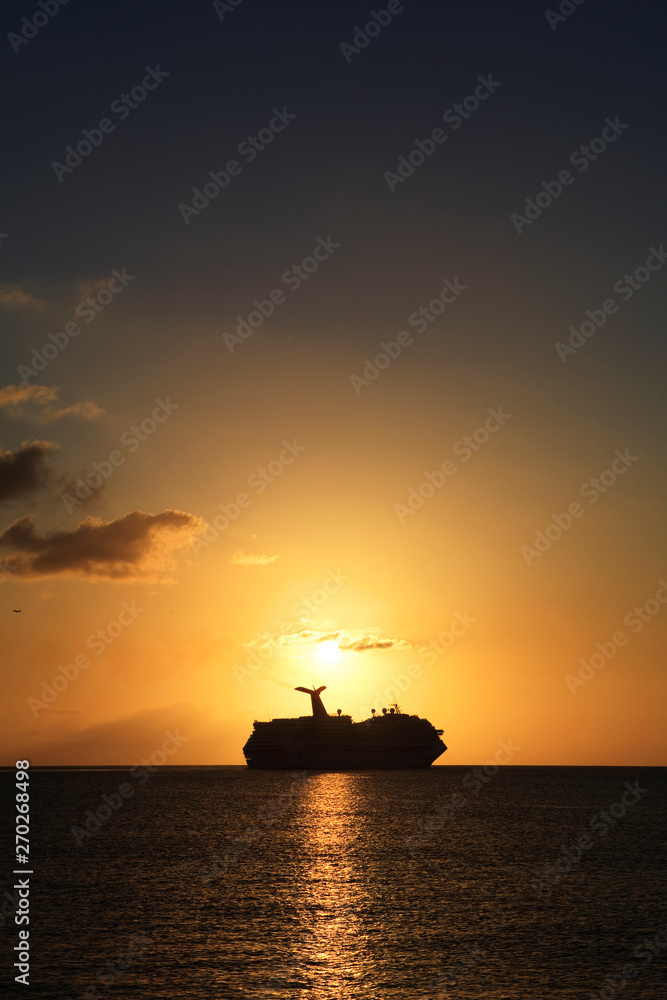 a cruise ship sails along the horizon at sunset