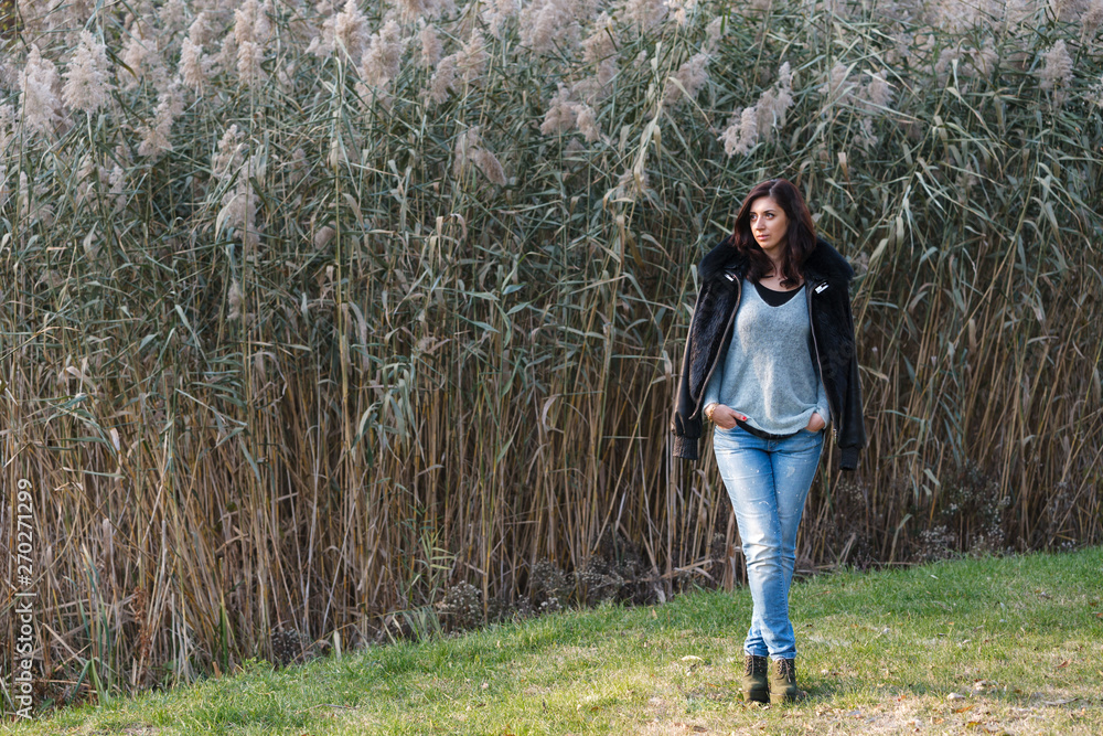 Beautiful brunette standing on a background of reeds. Beautiful brunette standing on a background of reeds.