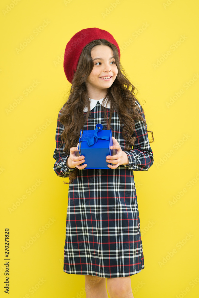 Fototapeta premium shopping. child with present box. happy birthday. . Holiday gift. parisian child on yellow background. happy girl with long curly hair in beret. small girl in french style hat. Choosing the best
