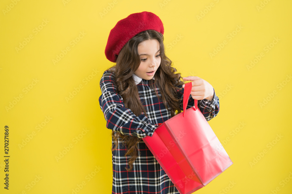 Just a minute of surprise. Little girl looking for surprise gift on yellow background. Small child holding shopping bag with surprise. Adorable shopper with surprise emotion on face Just a minute of surprise. Little girl looking for surprise gift on yellow background. Small child holding shopping bag with surprise. Adorable shopper with surprise emotion on face
