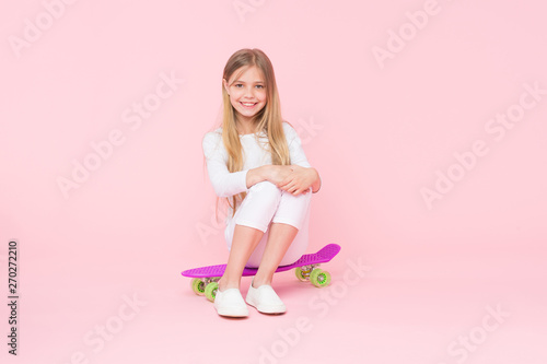 Billede på lærred Girl having fun with penny board pink background