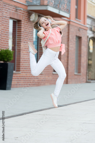 Dancing cutie. Adorable dancer moving to music on city street. Small child enjoy dancing to modern music. Energetic little girl dancing with pleasure. Listening dancing music