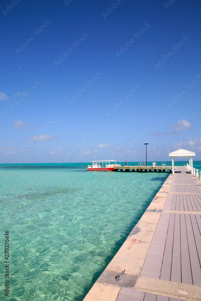Vacation dream. view along a Caribbean Jetty towards a cabana and a couple of boats.