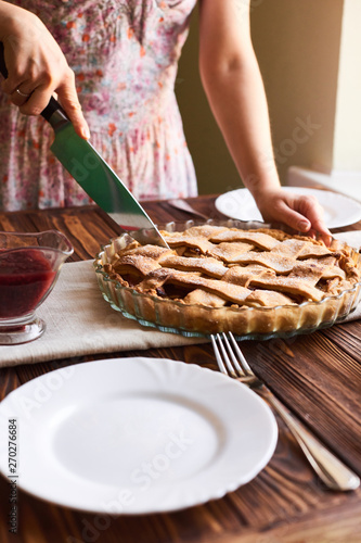 woman cutting a dessert of freshly baked apple pie on wooden the table