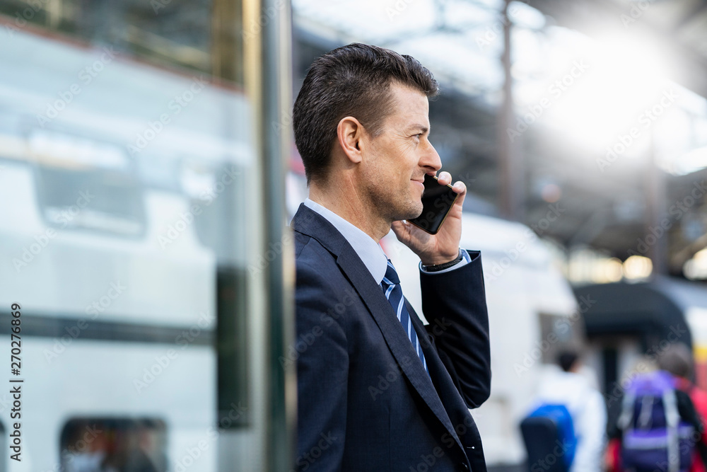 Businessman on cell phone at train station Businessman on cell phone at train station