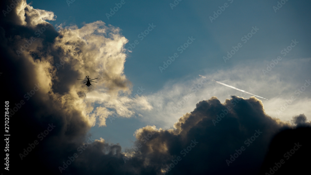 Silhouette of helicopter in flight against dramatic sky and clouds Silhouette of helicopter in flight against dramatic sky and clouds