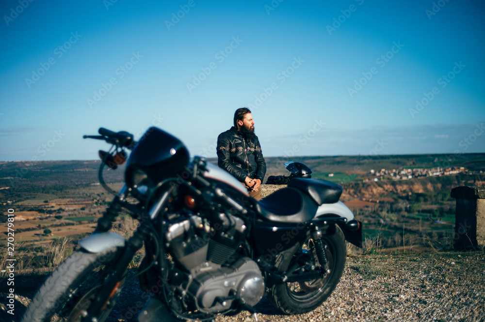 Man with custom motorcycle having a break at sunset Man with custom motorcycle having a break at sunset