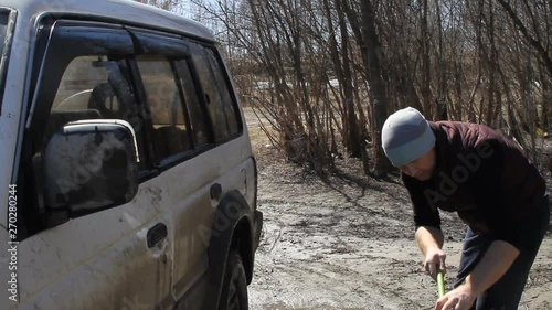 a man washing an SUV with a MOP and a rag from the bucket on the river photo