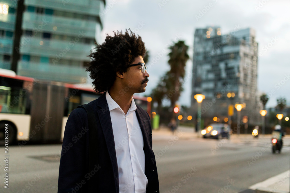 Spain, Barcelona, businessman standing at a street in the city at dusk Spain, Barcelona, businessman standing at a street in the city at dusk