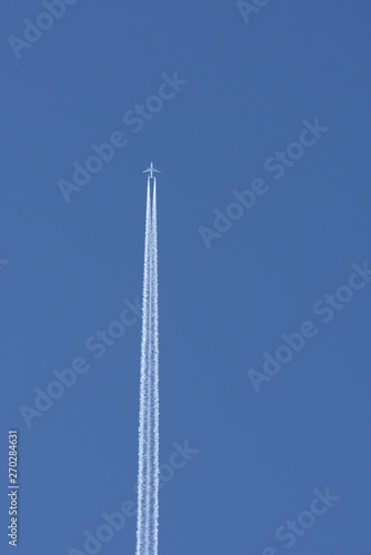 Straight vertical airplane trail in clear blue sky