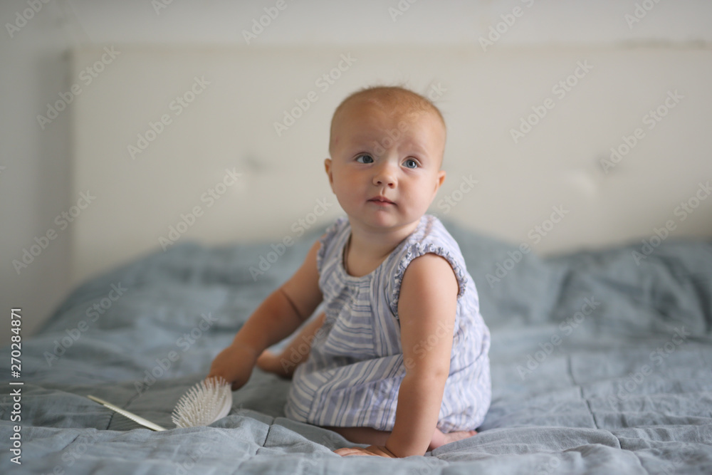 Fototapeta premium Bald Caucasian baby 10 months playing with comb