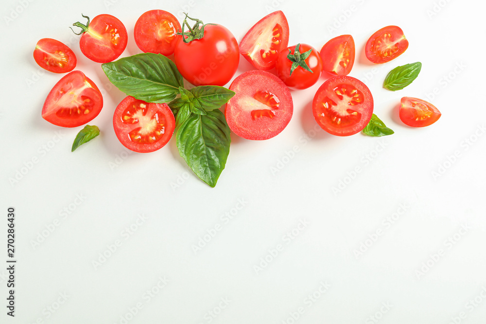 Fototapeta premium Flat lay composition with fresh cherry tomatoes and basil on white background, space for text. Ripe vegetables