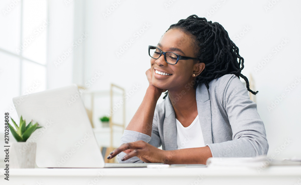 African-American Woman Looking At Laptop Screen In Office African-American Woman Looking At Laptop Screen In Office