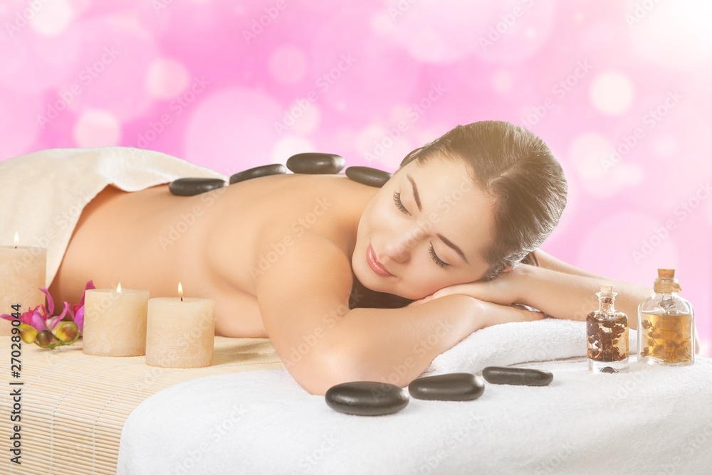 Beautiful young woman relaxing with stone massage at beauty spa Beautiful young woman relaxing with stone massage at beauty spa
