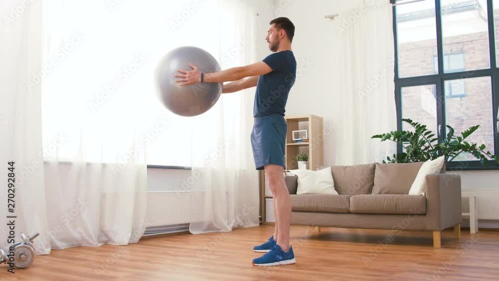 fitness, sport and healthy lifestyle concept - man exercising and doing squats with ball at home fitness, sport and healthy lifestyle concept - man exercising and doing squats with ball at home