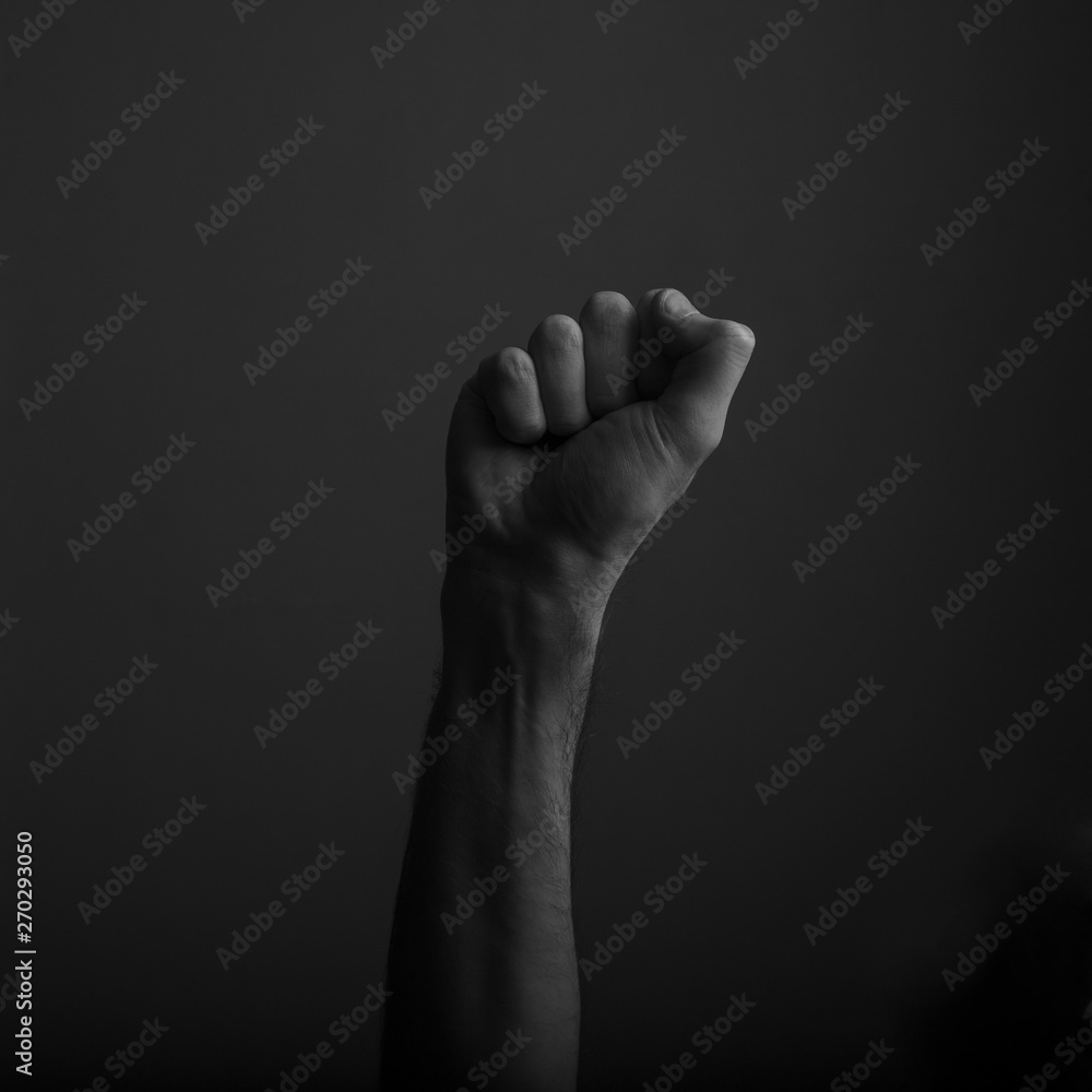 Raised clenched fist against a dark background, power, protest concept Raised clenched fist against a dark background, power, protest concept