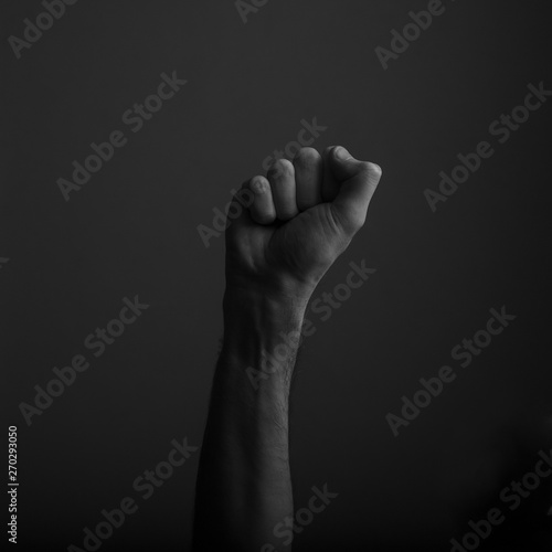 Raised clenched fist against a dark background, power, protest concept