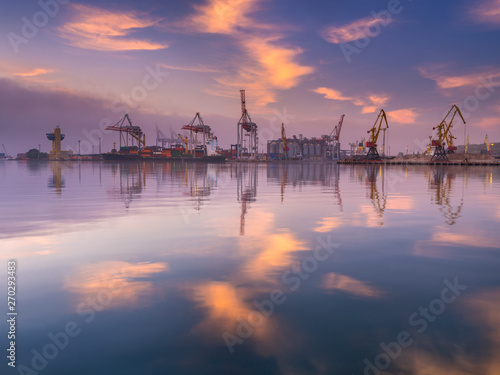 sun spots on the water and in the sky above sea port in sunrise