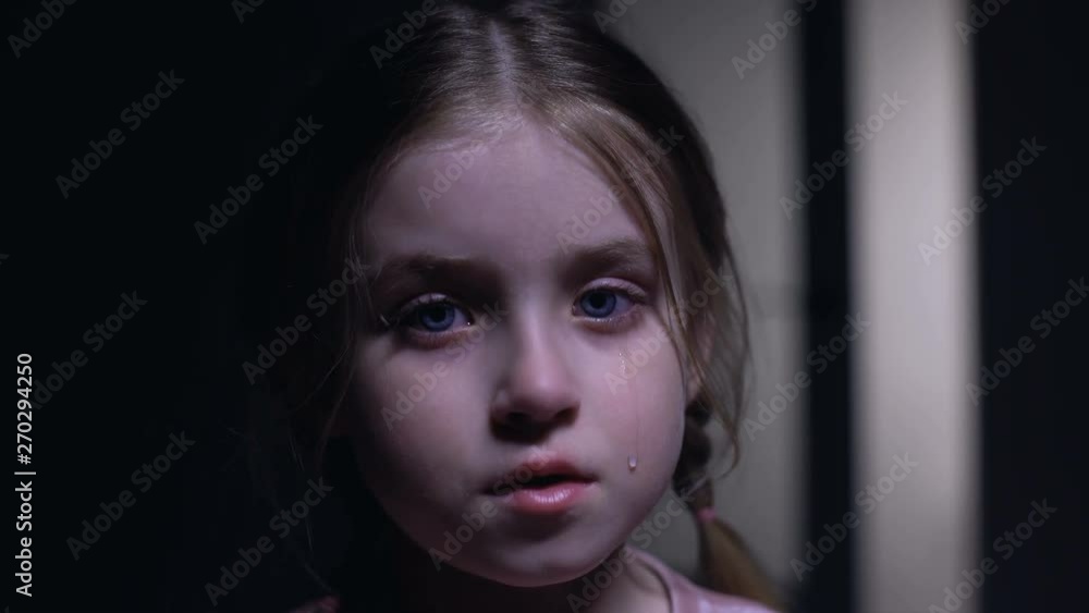 Little crying girl looking at camera, victim of domestic violence, childs rights Little crying girl looking at camera, victim of domestic violence, childs rights